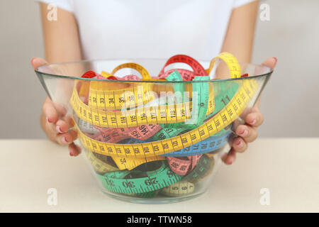 Woman holding bowl with measuring tape sur fond blanc Banque D'Images