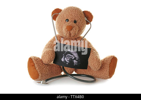 Ours en peluche avec échographie de bébé et stéthoscope sur fond blanc Banque D'Images