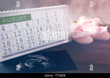 Calendrier avec balayage d'ultrasons de chaussures pour bébés et enfants on wooden table Banque D'Images