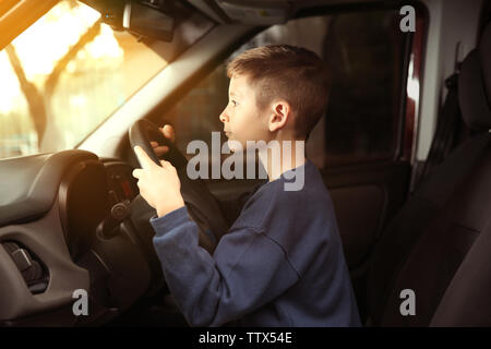 Cute little boy faire semblant de conduire une voiture Banque D'Images