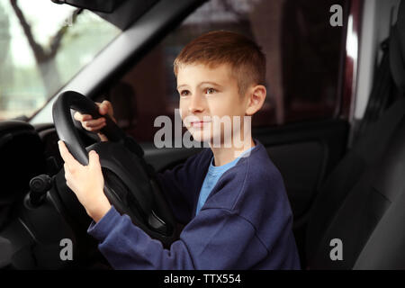 Cute little boy faire semblant de conduire une voiture Banque D'Images