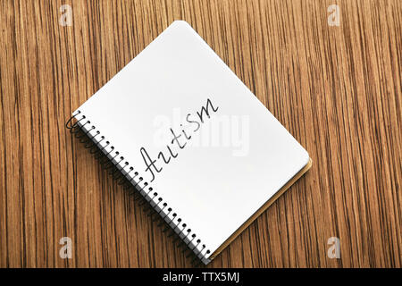 Autisme mot écrit en portable sur fond de bois, vue du dessus Banque D'Images