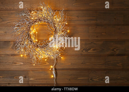 Belle couronne de Noël avec shining garland sur fond de bois Banque D'Images