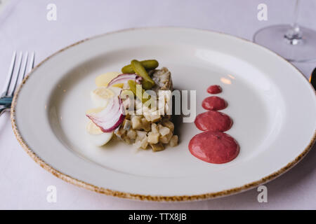 Restaurant délicatesse capsule sur le nappe violet. Plaque blanche avec le hareng Banque D'Images