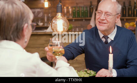 Joli couple de personnes âgées faire des toasts et clinking glasses. Manger au restaurant. L'homme et de la femme dans la soixantaine. Banque D'Images