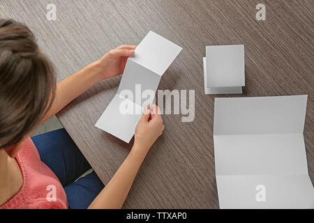 Femme assise à table en bois avec livrets vierges Banque D'Images