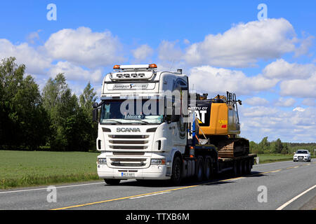 Humppila, Finlande. Le 31 mai 2019. Scania R620 personnalisé blanc chariot Konepaja Survonen parcours CAT 320F excavateur hydraulique sur la remorque sur la route d'été. Banque D'Images