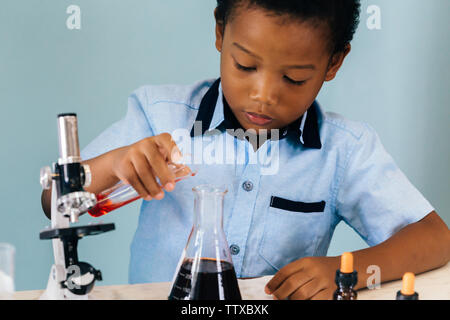 African American boy de potion de mélange des produits chimiques et la chimie de l'apprentissage in laboratory Banque D'Images