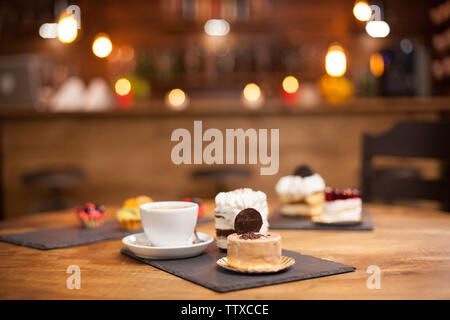 Diverses tranches de délicieux gâteaux sur une table en bois dans un café. Tranche de gâteau savoureux biscuit avec sur le dessus. Une délicieuse tasse de café. Banque D'Images