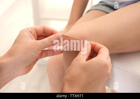 L'application de plâtre sur les mains des femmes girl's knee, gros plan Banque D'Images