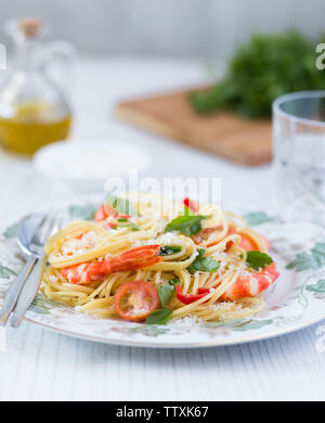 Belle assiette avec une assiette de crevettes fraîches, des pâtes avec des herbes vertes et d'huile dans l'arrière-plan Banque D'Images