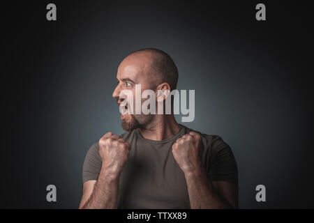 L'homme se présentant comme un gagnant et avec une tête de profil. Studio shot. Concept de la victoire et le succès. Banque D'Images