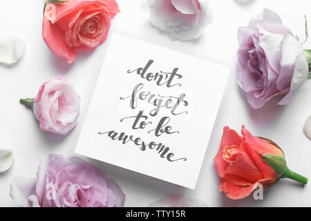 Inscription 'NE PAS OUBLIER D'ÊTRE GÉNIAL" écrit sur support papier avec des fleurs sur fond blanc Banque D'Images