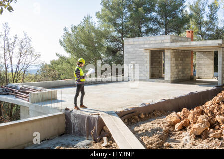 Apprenti artisan, bâtiment contrôle un plan sur un site de construction de la maison en construction Banque D'Images