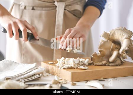 Champignons coupe femme sur planche de bois à cuisine, closeup Banque D'Images