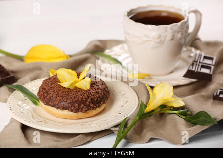 De délicieux beignets au chocolat, tasse de café et de fleurs jaunes sur le tableau blanc et de serviette gris Banque D'Images