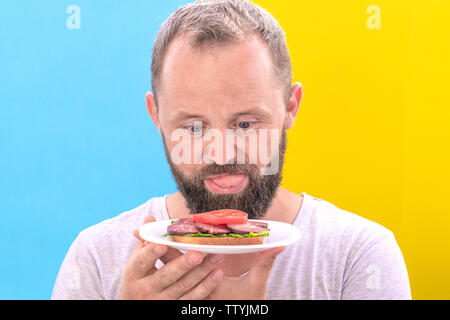 Penser à ce que l'homme à barbe drôle de manger entre une pomme et un gâteau. Diett concept. Banque D'Images