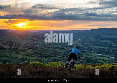 Un homme rides un ebike depuis le sommet de l'Ardanaiseig dans les Brecon Beacons, près d'Abergavenny, Monmouthshire, Wales. Randonnée cycliste du Pays de Galles. Banque D'Images