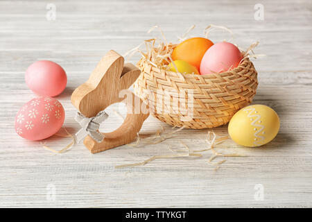 Panier avec les oeufs de Pâques colorés et bunny figure sur fond de bois Banque D'Images