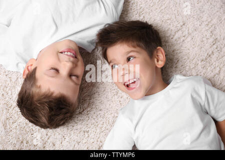 Cute little brothers allongé sur le tapis à la maison Banque D'Images