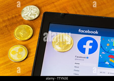 PRAGUE, RÉPUBLIQUE TCHÈQUE - le 18 juin 2019 : Golden ripple, bitcoin et pièces ethereum allongé sur page d'accueil de Facebook lancement digital wallet Calibra et cr Banque D'Images