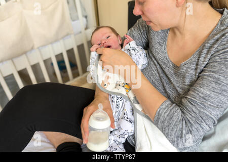 Jeune mère de nourrir bébé nouveau-né. Femme bébé lingettes visage et rss par bouteille de lait Banque D'Images