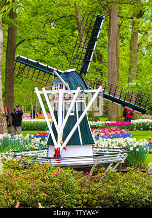 Keukenhof, Lisse, Pays-Bas - 28 Apr 2019 : Moulin entouré de fleurs colorées dans les célèbres jardins de Keukenhof. Les gens en arrière-plan. Le parc est un lieu touristique populaire. Banque D'Images