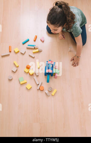 Vue de dessus d'un enfant petite fille jouant sur le plancher avec bloc de construction en bois jouets à la maison ou au jardin d'enfants, de jouets éducatifs pour enfants créatifs, Banque D'Images