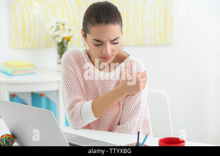 Belle jeune femme souffrant de douleur à l'épaule dans office Banque D'Images