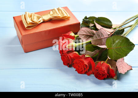 De belles roses rouges et boîte-cadeau sur fond de bois Banque D'Images