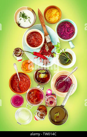 Assortiment d'épices principalement rouge et blanc à l'intérieur de sauces salées bols et autres contenants sur fond vert Banque D'Images