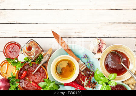 Frontière avec une sélection de sauces et marinades à l'aide de fines herbes, d'épices et d'assaisonnements en bouteilles sur le bois blanc rustique with copy space Banque D'Images