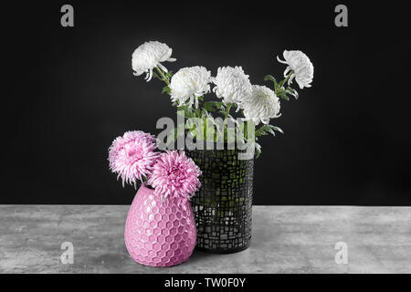 Deux vases avec de belles fleurs sur fond sombre Banque D'Images