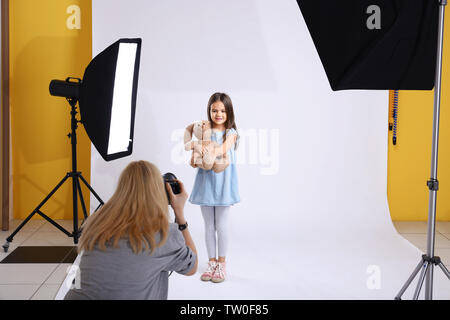 La prise de photo photographe cute little girl avec ours en peluche sur fond clair Banque D'Images