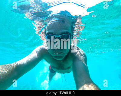 Vue sous-marine d'un plongeur jeune homme nager dans la mer. Des bulles d'air sortant de la bouche et le nez Banque D'Images