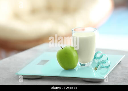 Verre de lait, apple, bande de mesure et les balances sur table de cuisine Banque D'Images