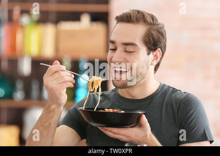 Bel homme de manger des pâtes à la maison Banque D'Images
