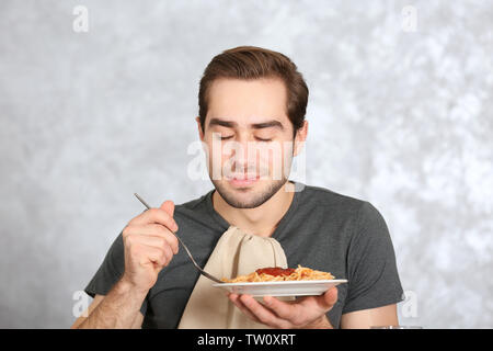 Bel homme de manger des pâtes sur fond clair Banque D'Images