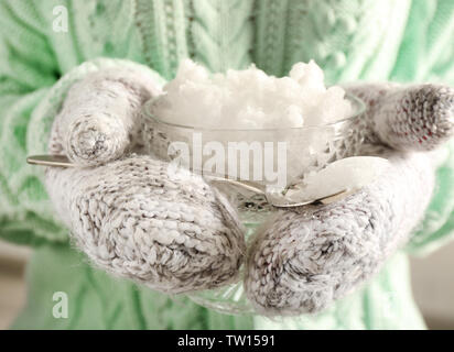 Les mains dans les moufles holding bowl cristal de neige closeup Banque D'Images