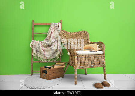 Fauteuil en osier et décoratif de bain avec motif à carreaux sur fond de mur vert Banque D'Images