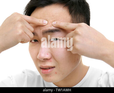 Young Asian man popping boutons, sur fond blanc Banque D'Images