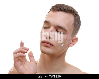 Beau jeune homme, l'application de la crème pour les peaux à problèmes sur une face, sur fond blanc Banque D'Images