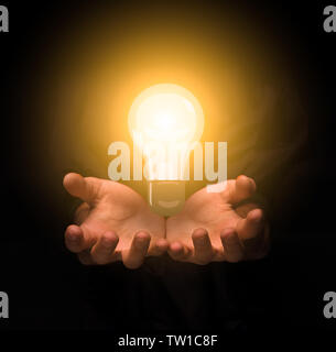 Nouvelle idée concept. Les femmes hands holding glowing lightbulb dans l'obscurité Banque D'Images