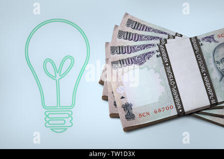 Lightbulb with bundles of hundred rupees banknotes Stock Photo