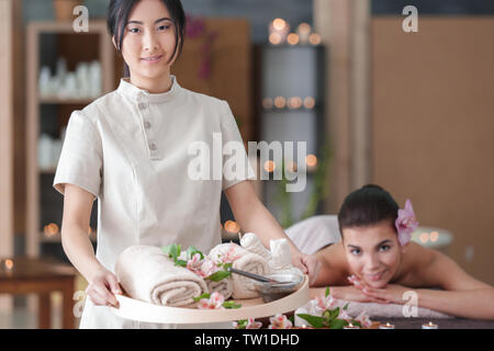 Belle asiatique masseur holding tray with spa produits de thérapie dans un centre de bien-être Banque D'Images