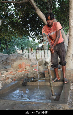 Adolescent tenant une pompe à eau, Inde Banque D'Images