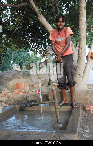 Un adolescent tirant de l'eau d'une pompe à eau, Inde Banque D'Images