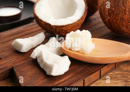Noix de coco et la cuillère d'huile sur planche de bois Banque D'Images