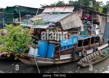 Une péniche traditionnelle vietnamienne de transporter des noix de coco et bananes sur la rivière Saigon, contenant des objets de famille comme les jouets pour enfants et des plantes Banque D'Images