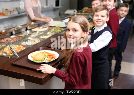 Belle petite fille recevant de la nourriture dans la cafétéria de l'école Banque D'Images